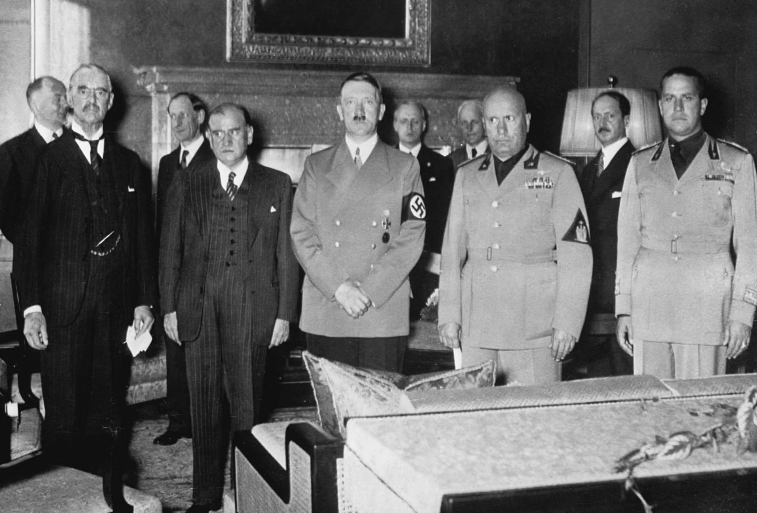 Historická fotografie skupiny světových vůdců, včetně Adolfa Hitlera a Benita Mussoliniho, na oficiální schůzce.